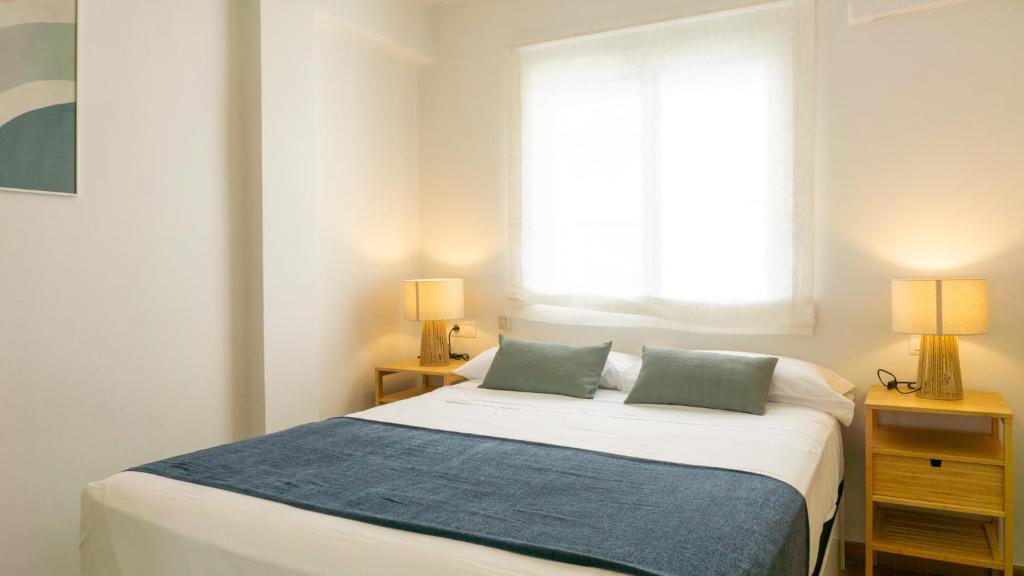 een slaapkamer met een bed met 2 lampen en een raam bij Elegant Malaga Retreat in Málaga
