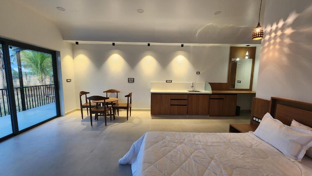 Cet appartement comprend une chambre avec un lit, une cuisine et une table. dans l'établissement Amrutiya Farmview Suit, à Bhuj