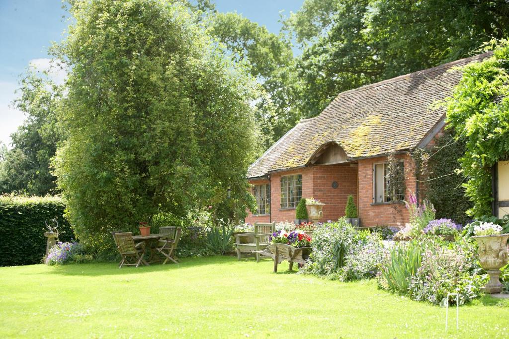een huis met een tafel en stoelen in een tuin bij Long Cover Cottage in Tenbury