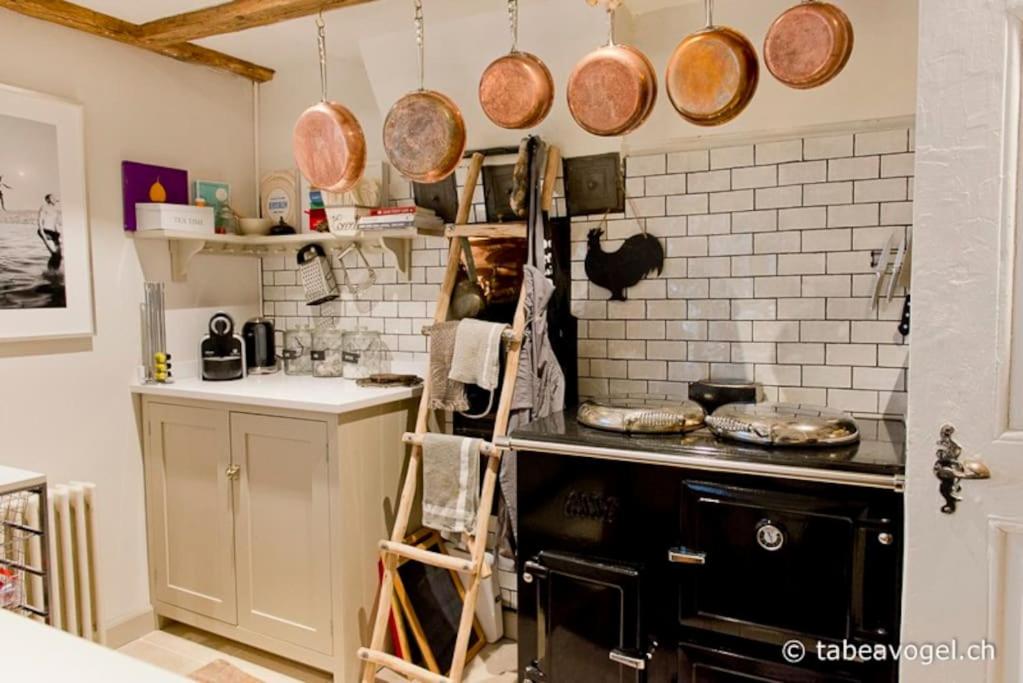 a kitchen with a stove and pots and pans on the wall at Luxury 250 yr old Swiss farm with wine cellar in Rüschlikon