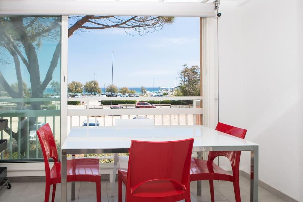 - une table blanche et des chaises rouges dans une chambre avec fenêtre dans l'établissement Escapade Marine : Vue mer, 2 chambres, Parking, à pied de la plage, à Sainte-Maxime