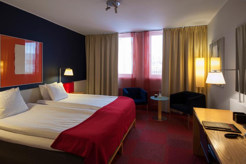 a hotel room with a large bed and a desk at ProfilHotels President in Norrköping