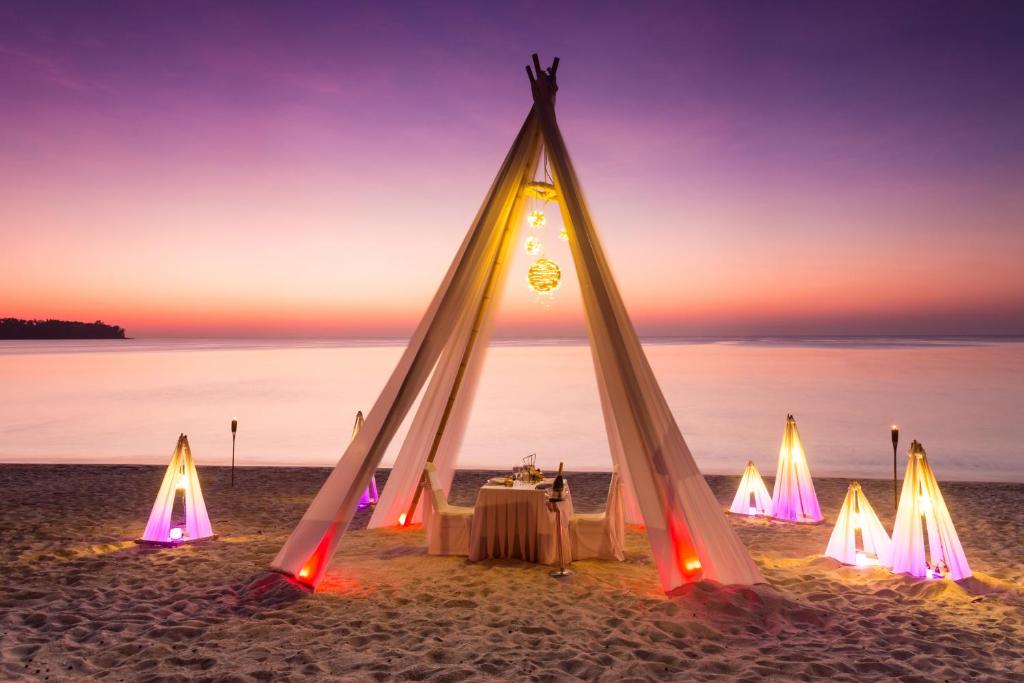 a dinner table in a teepee on the beach at sunset at Dusit Thani Laguna Phuket in Bang Tao Beach