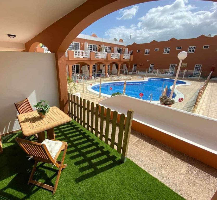 a balcony with a table and chairs and a swimming pool at El Olivar Caleta Mar in Caleta De Fuste