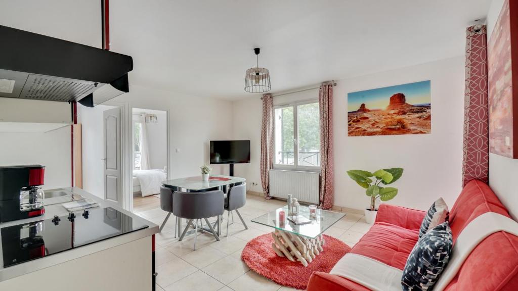 ein Wohnzimmer mit einem roten Sofa und einem Tisch in der Unterkunft Chic apart with parking and balcony near Paris in Aubervilliers