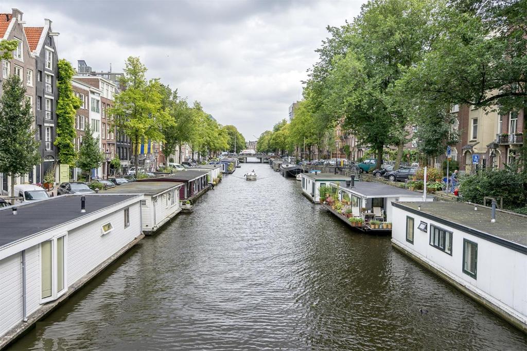 a canal with houses and a boat on it at Houseboat Orpheus in Amsterdam