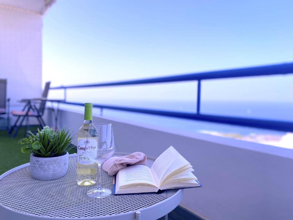 a table with an open book and a bottle of wine at Tropicalidays Paraiso Seafront in Playa Paraiso