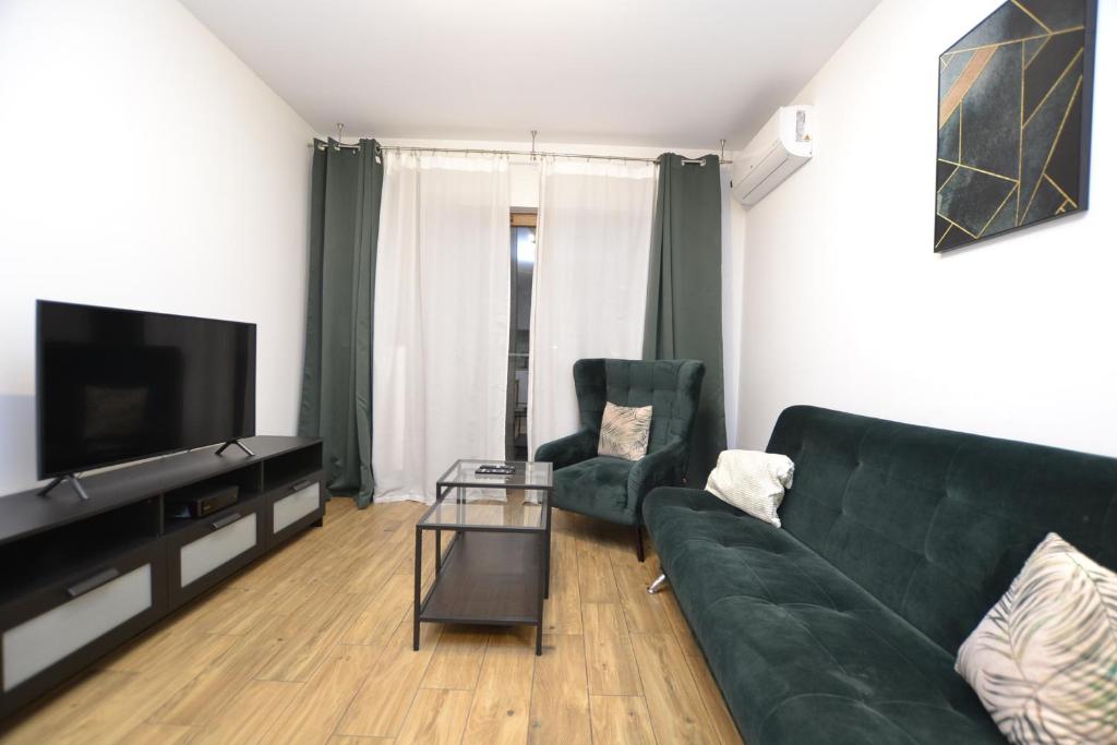 ein Wohnzimmer mit einem grünen Sofa und einem Fernseher in der Unterkunft Apartament SZMARAGDOWY z garażem Centrum Gliwic-Klimatyzacja in Gliwice