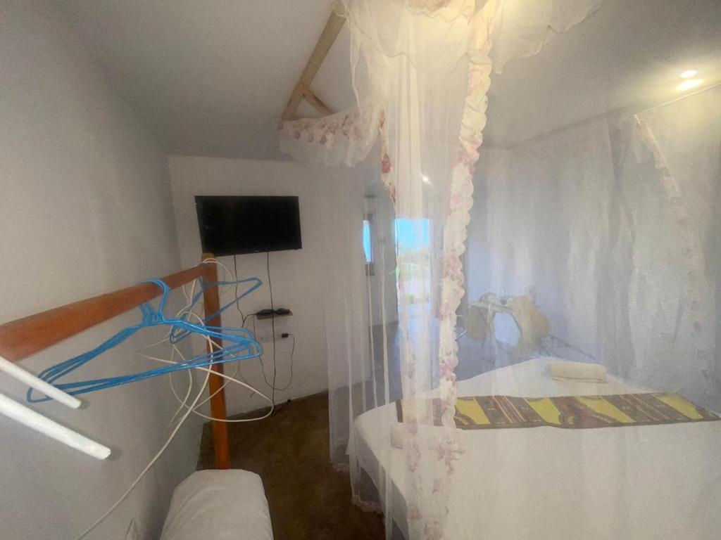 um pequeno quarto com uma cama com uma cortina em Aeropark Residencial (B&B) em Maputo