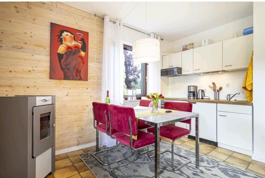 a kitchen with a dining table and red chairs at Apartment mit Kamin-Sonnendurchflutet-Balkon in Winterberg