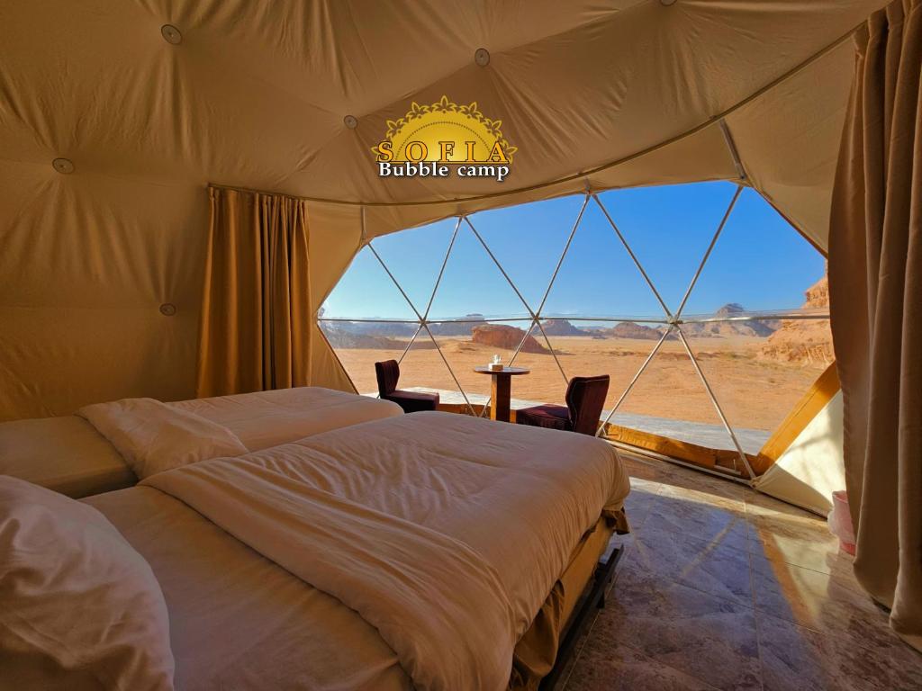two beds in a tent with a view of the desert at Bubble Sofia Luxury Rum Camp in Wadi Rum