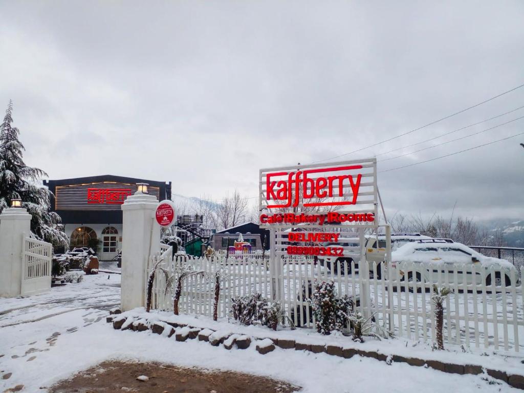 a white fence in front of a store in the snow at Kaffberry Cafe & Homestays in Kūd