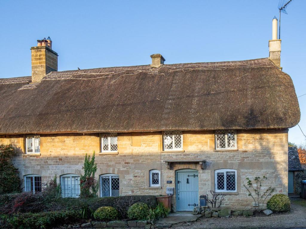 an old stone house with a thatched roof at Betty's Cottage in Burford