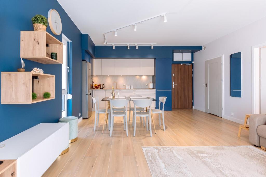cocina y sala de estar con paredes azules, mesa y sillas en Blue Sea en Pogorzelica