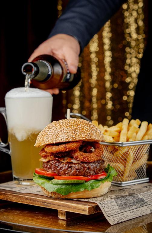 a person pouring a drink into a hamburger and french fries at FLY INN BAKU in Baku