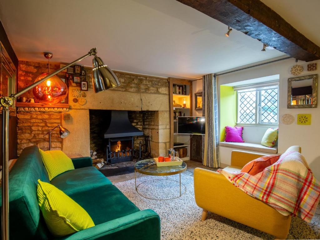 a living room with a green couch and a fireplace at Betty's Cottage in Burford