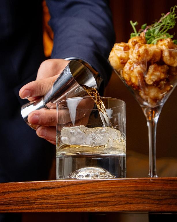 a person pouring a drink into a glass at FLY INN BAKU in Baku