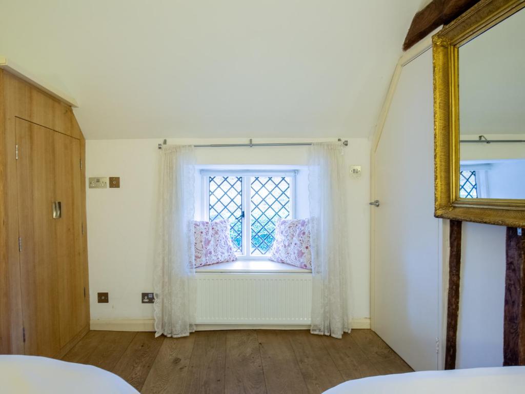 a room with a window with white curtains at Betty's Cottage in Burford