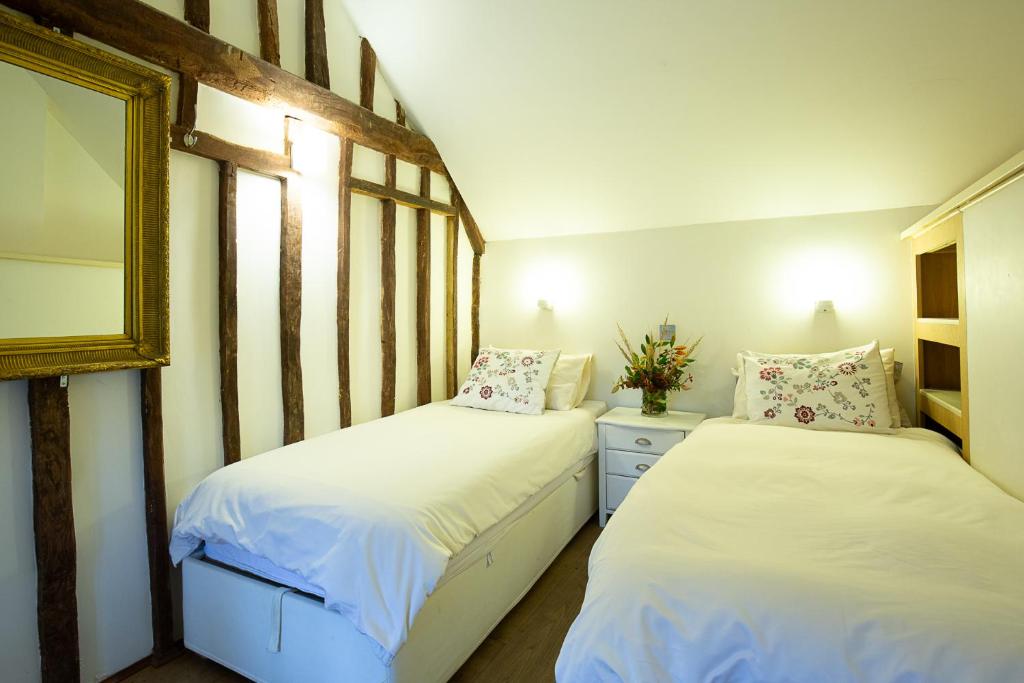 a bedroom with two beds and a mirror at Betty's Cottage in Burford