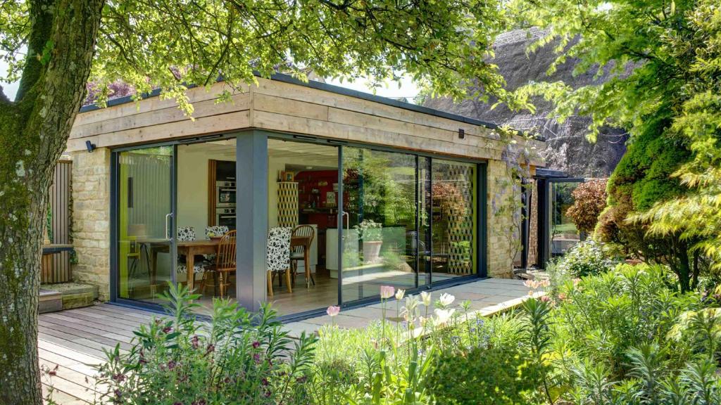 a small house with glass doors on a deck at Betty's Cottage in Burford