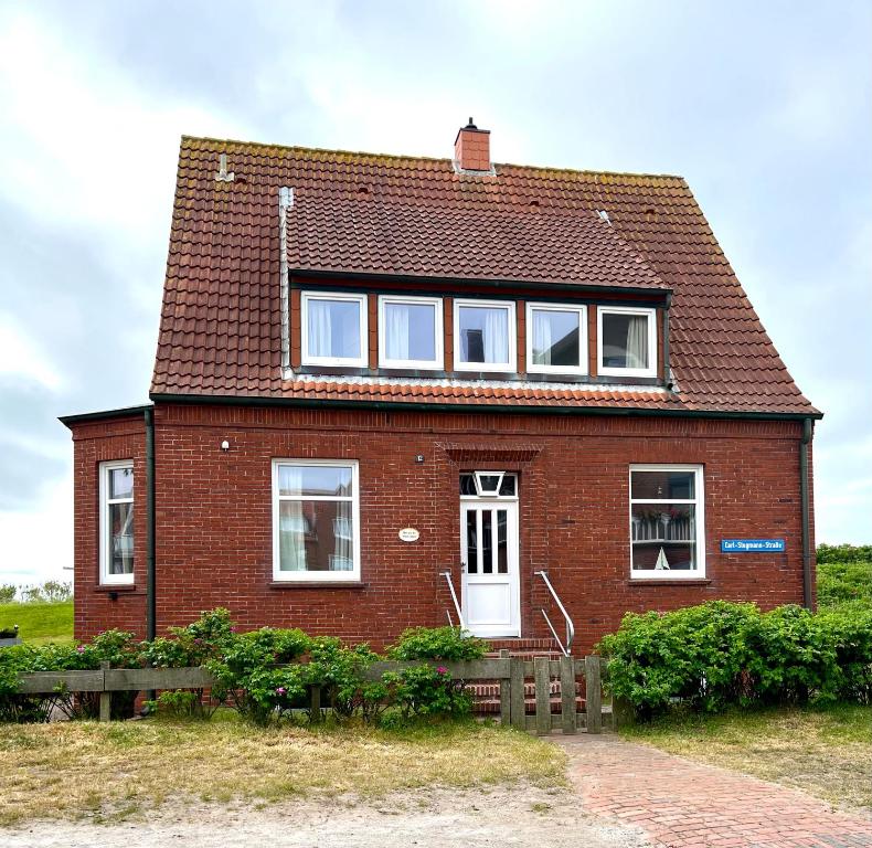 una casa de ladrillo rojo con ventanas blancas en un campo en Hus an de Waterkant, en Juist