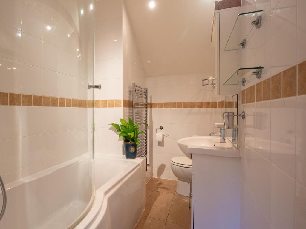 a bathroom with a tub and a toilet and a sink at Betty's Cottage in Burford