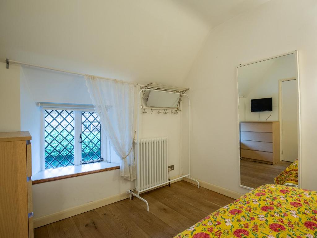 a bedroom with a bed and a window and a mirror at Betty's Cottage in Burford