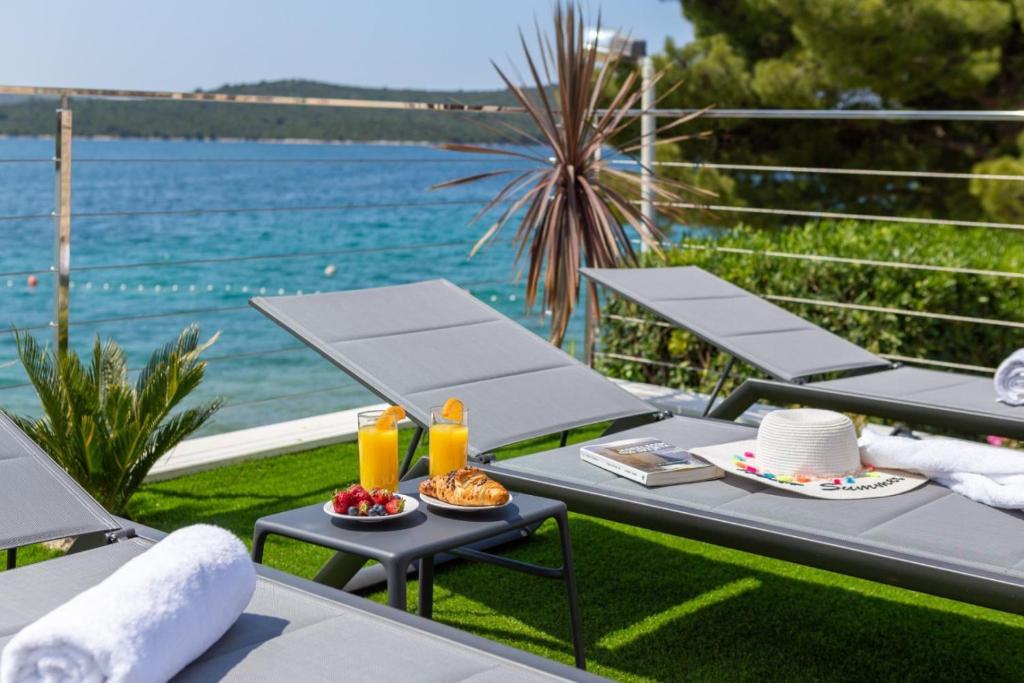 a table with food and drinks on a patio with the water at Luxury Seaside Villa L'Amour with pool in Sibenik - Zaboric in Zaboric