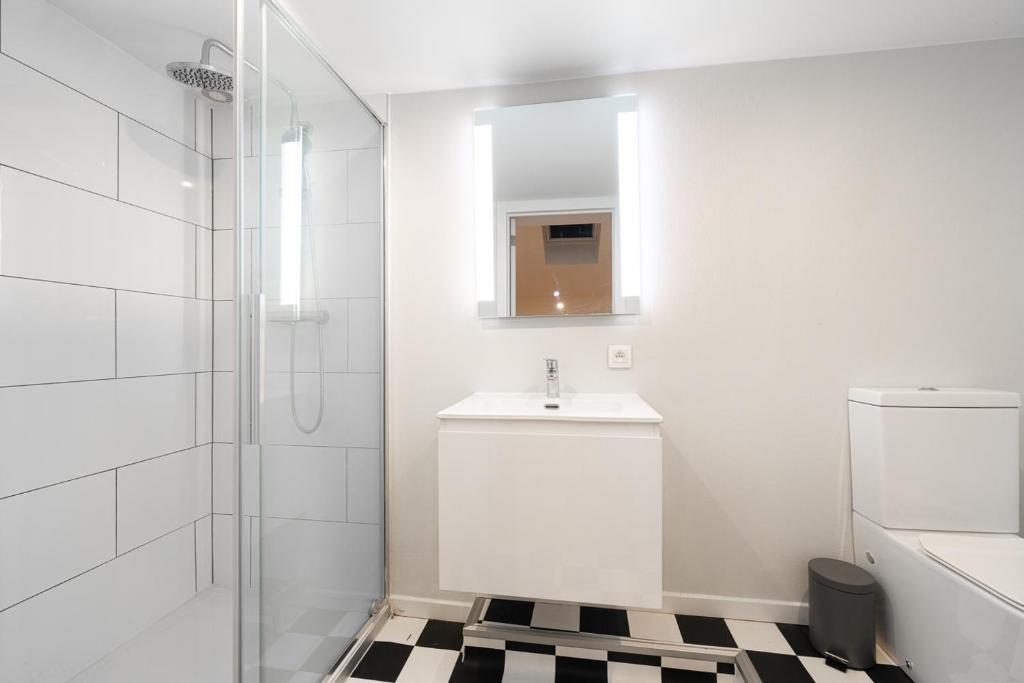 La salle de bains blanche est pourvue d'un lavabo et d'une douche. dans l'établissement Maison 4 chambres avec jardin, à Liège