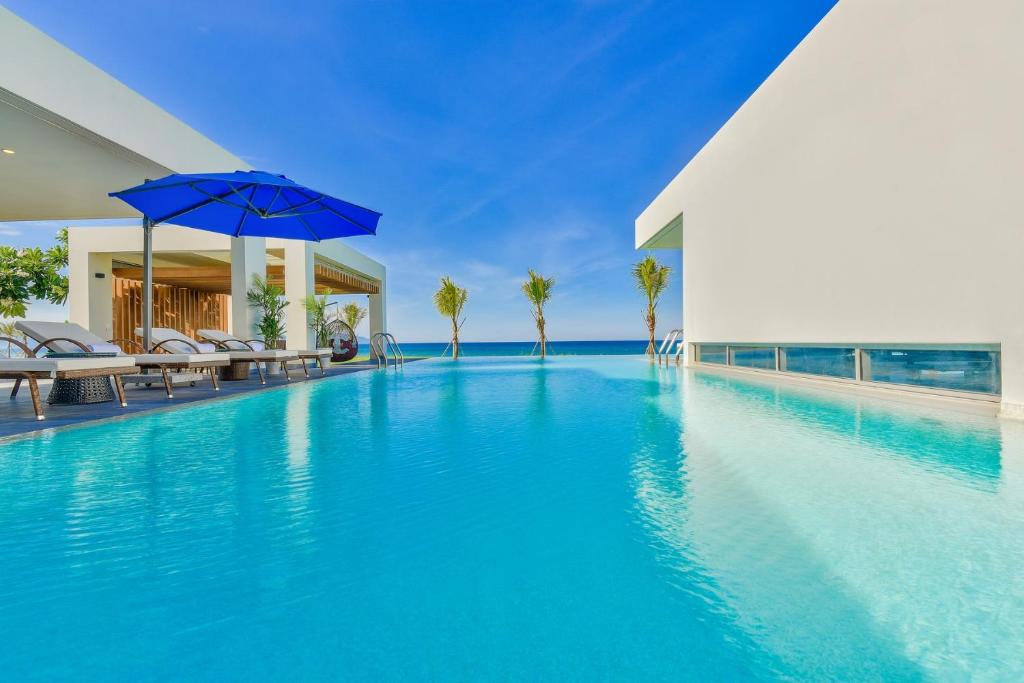 an infinity pool with chairs and an umbrella at Danang Amazing Ocean Villas in Da Nang