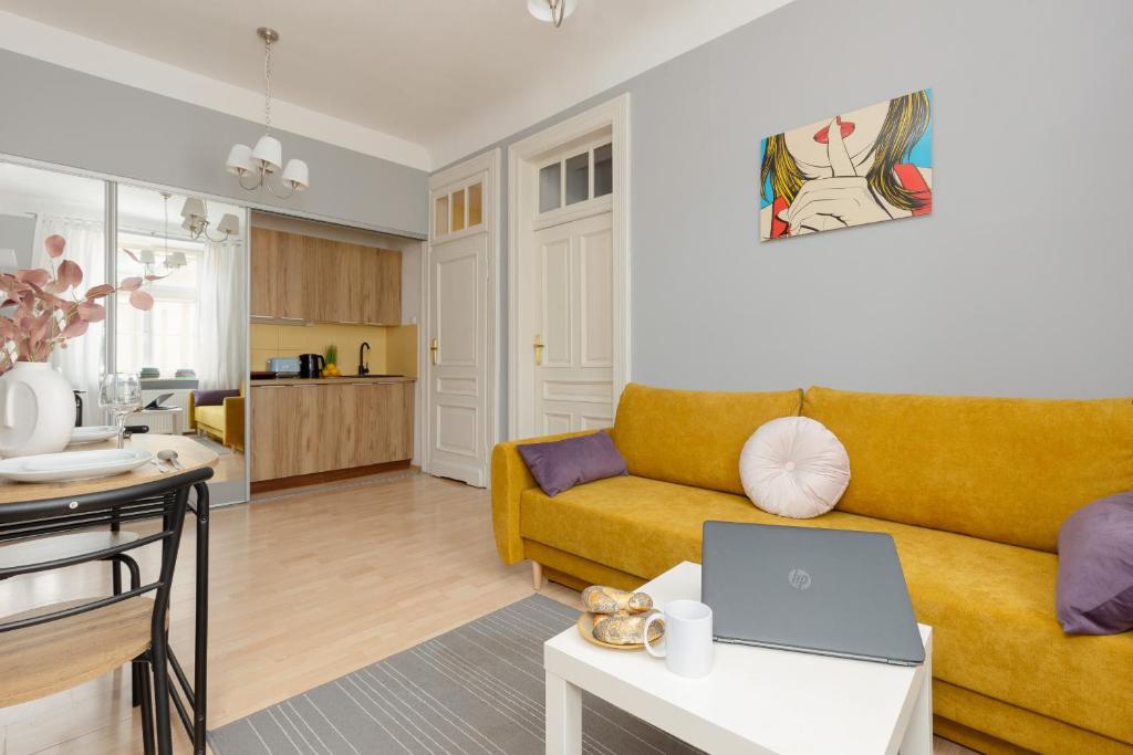 a living room with a couch and a table with a laptop at Sunny Studio Lwowska Street Metro by Renters in Warsaw