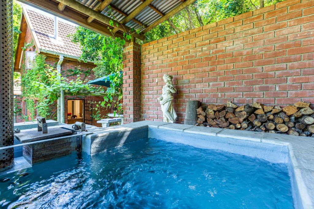 a swimming pool with a statue next to a brick wall at Devon Castle Orchard Cottage in Stellenbosch
