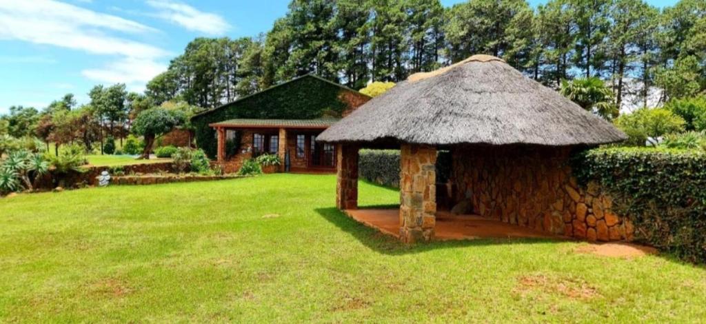 a small hut with a grass roof in a yard at The Ivy Cottage at Random Rocks Farm in Tonteldoos