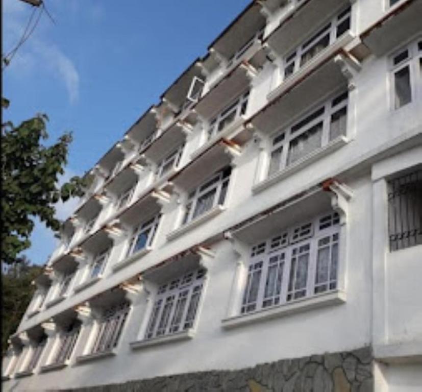 een wit gebouw met ramen en een dak bij Royoporus Taktsang Darjeeling in Darjeeling