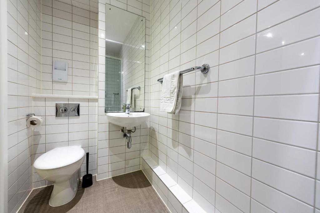 a white tiled bathroom with a toilet and a sink at University of Bath City Accommodation in Bath