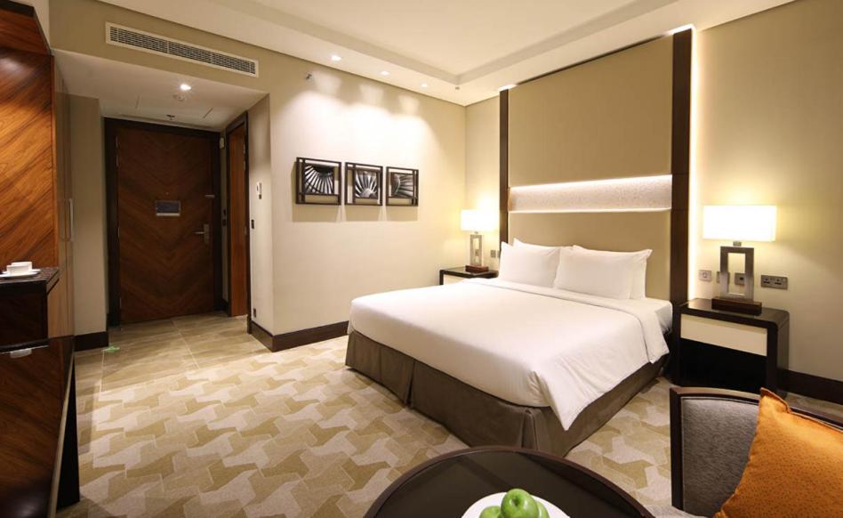 a hotel room with a large bed and a table at Aerotel Jeddah in Jeddah