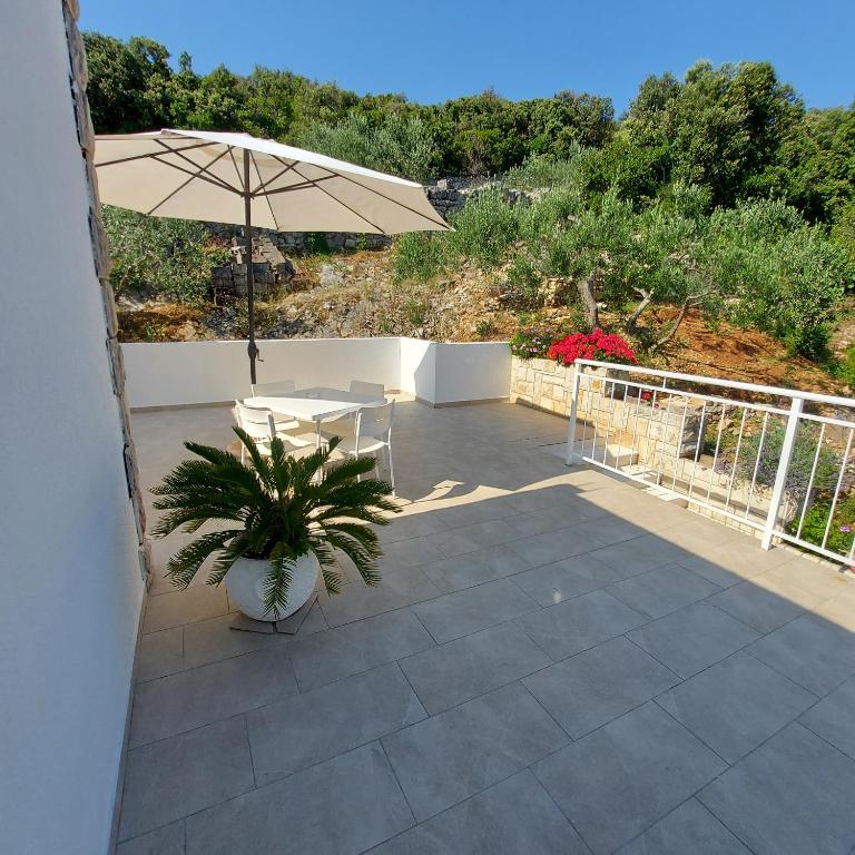 a patio with a table and an umbrella at Villa Šolta in Rogač