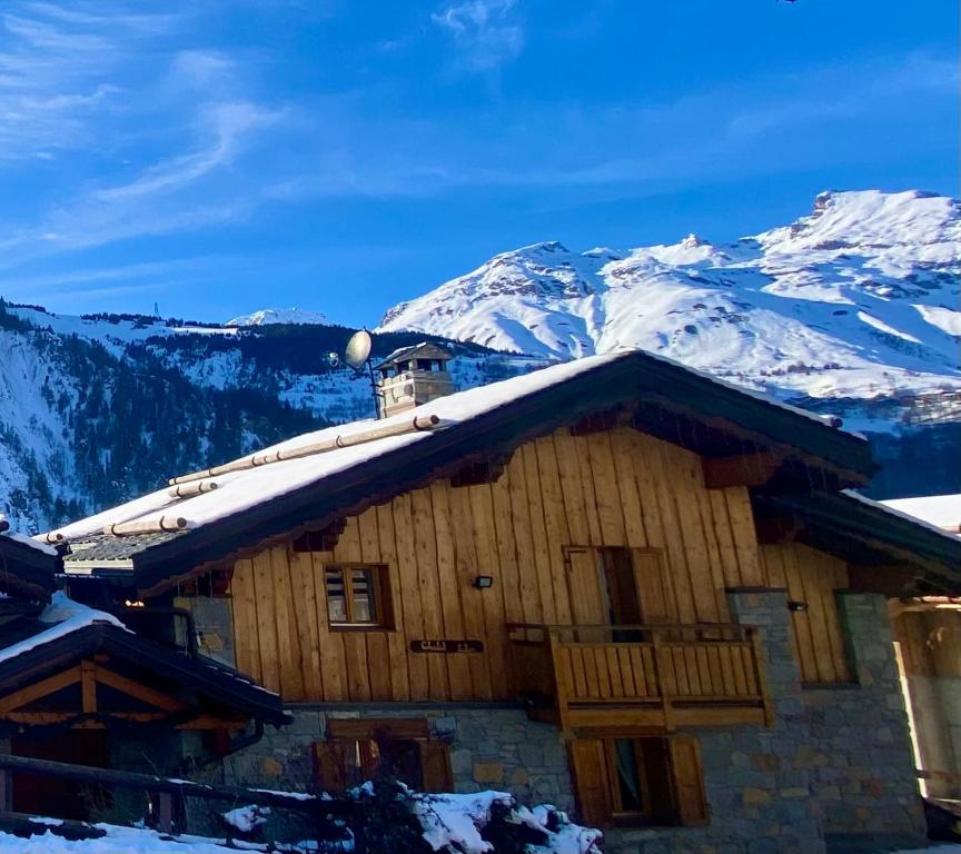 a log cabin with snow covered mountains in the background at Chalet 12 personnes st martin de Belleville 3 vallées in Béranger