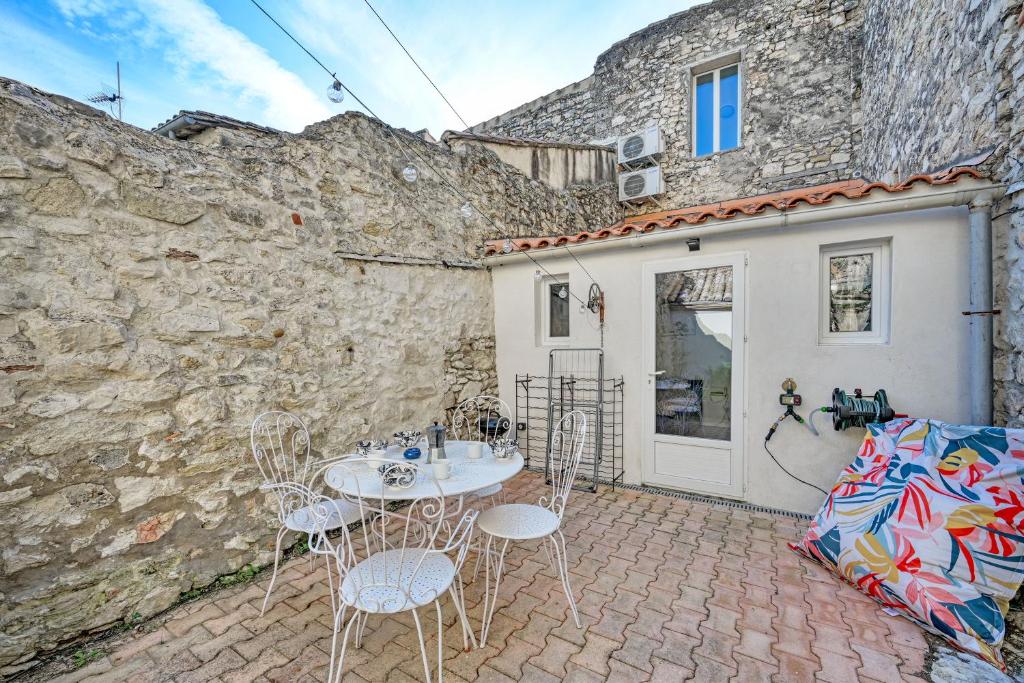 a patio with a table and chairs next to a building at La Cigale - Vieux Village - Charmante Maisonnette climatisée avec Jardin in Villeneuve-lès-Avignon