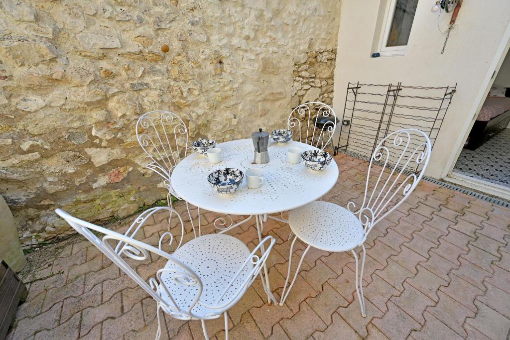 a white table and chairs on a patio at La Cigale - Vieux Village - Charmante Maisonnette climatisée avec Jardin in Villeneuve-lès-Avignon