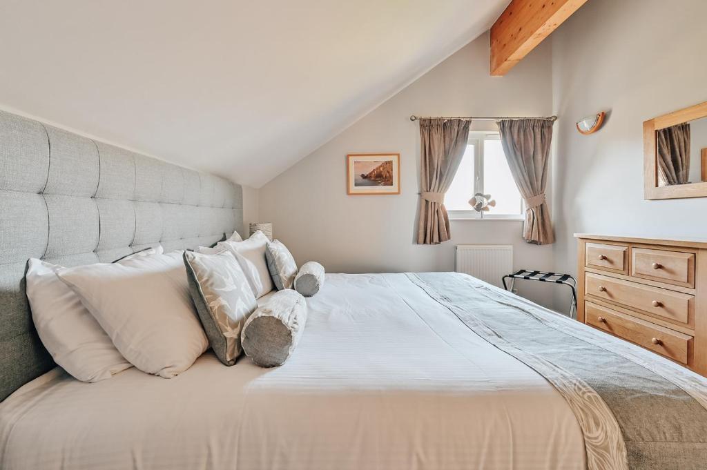 1 dormitorio con 1 cama grande con almohadas blancas en Swallow Lodge with Hot Tub, dogs welcome sleeps 8, Great resort Facilities en Padstow