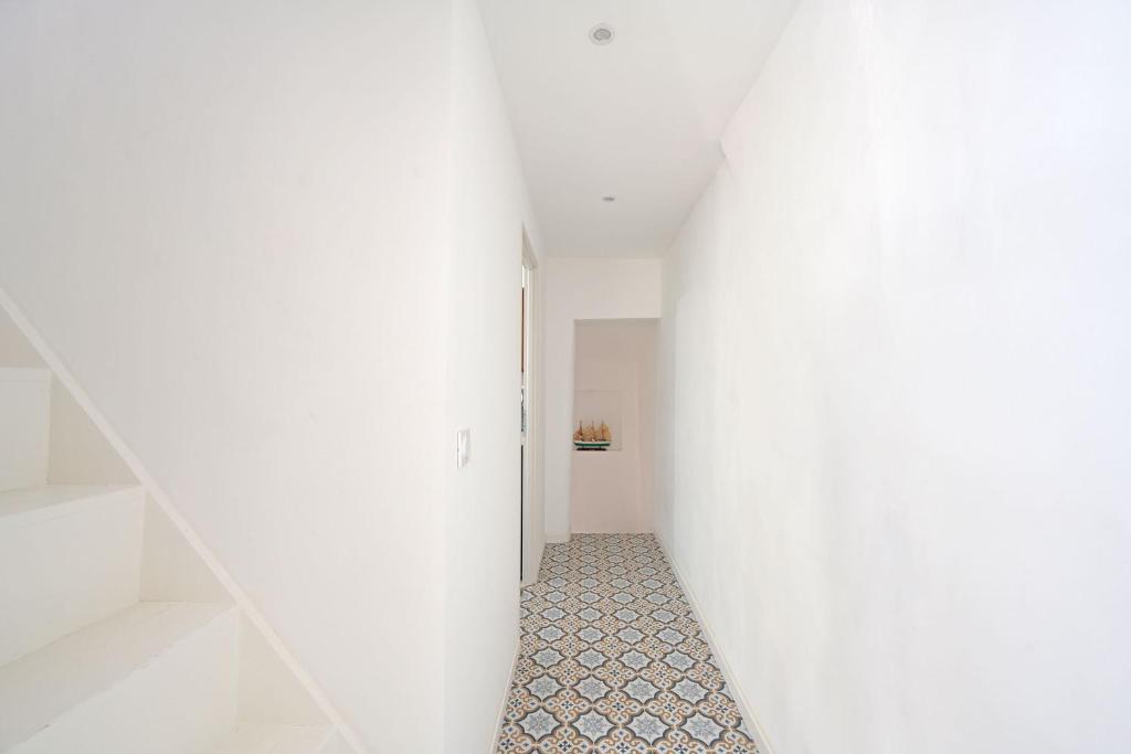 a hallway with a white wall and a tile floor at La Cigale - Vieux Village - Charmante Maisonnette climatisée avec Jardin in Villeneuve-lès-Avignon