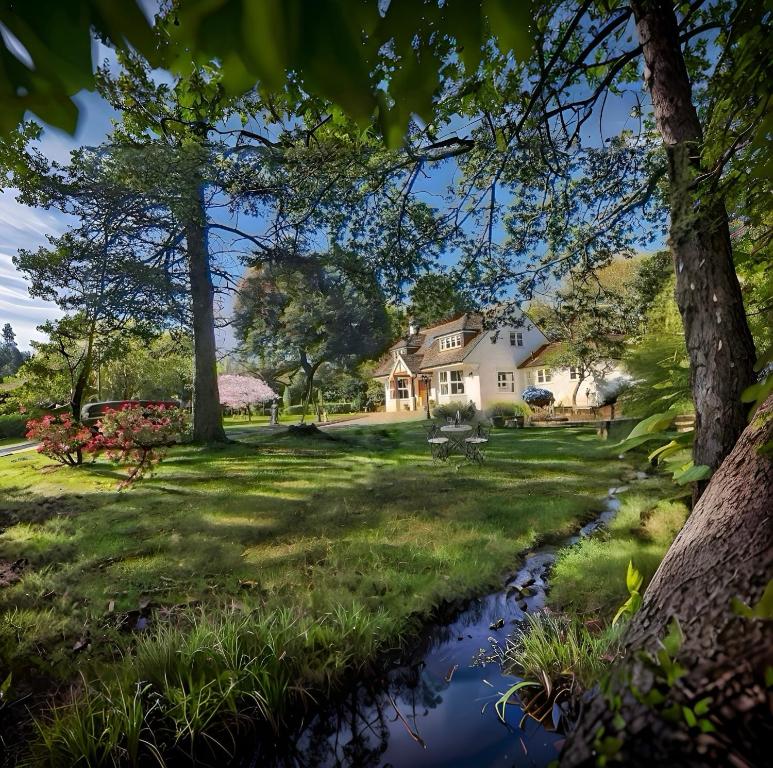 a house with a stream in the yard at Daweswood - Luxury cottage, lake access & hot tub in Canterbury