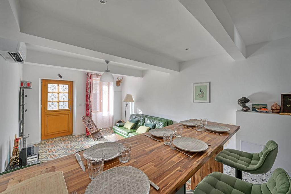 a dining room with a wooden table and green chairs at La Cigale - Vieux Village - Charmante Maisonnette climatisée avec Jardin in Villeneuve-lès-Avignon