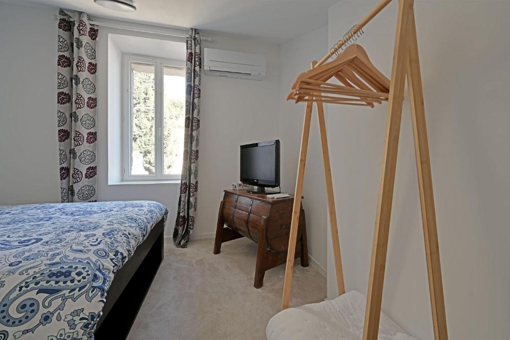 a bedroom with a bed and a tv on a dresser at La Cigale - Vieux Village - Charmante Maisonnette climatisée avec Jardin in Villeneuve-lès-Avignon