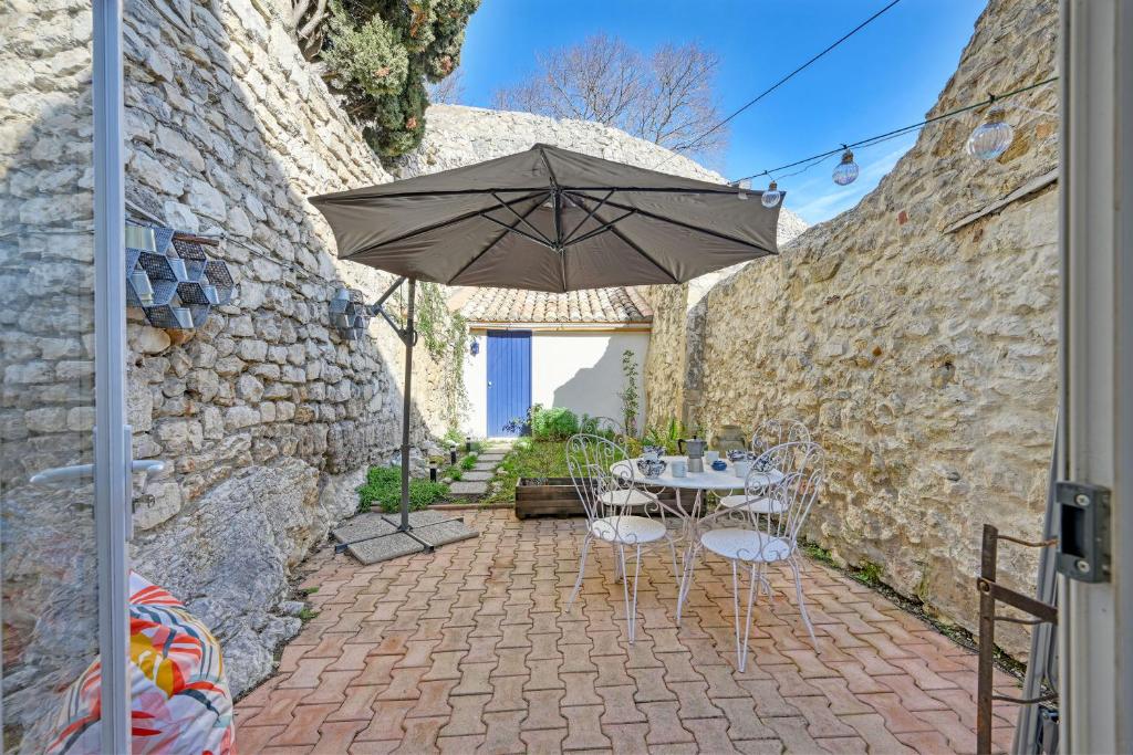 a patio with a table and an umbrella at La Cigale - Vieux Village - Charmante Maisonnette climatisée avec Jardin in Villeneuve-lès-Avignon