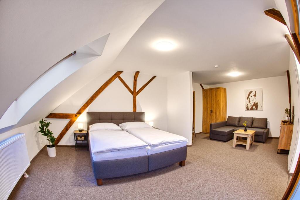 um quarto com uma cama e um sofá num quarto em Hotel a Restaurace Růže em Podbořany