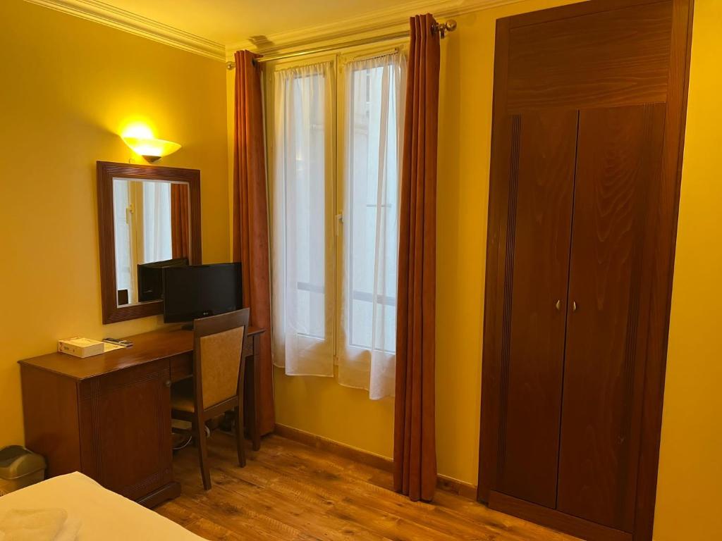 a bedroom with a desk and a mirror and a window at 121 Paris Hotel in Paris