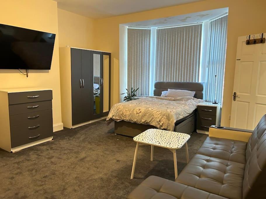 a bedroom with a bed and a couch and a tv at Ensuite Room with Private Bathroom at Walsall in Walsall