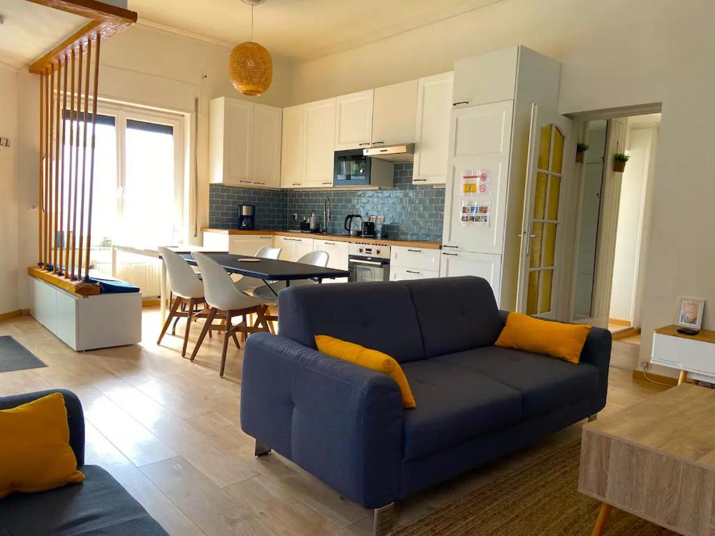 ein Wohnzimmer mit einem blauen Sofa und einer Küche in der Unterkunft Maison Cosy 6 chambres 2 SDB toute commodité in Roubaix
